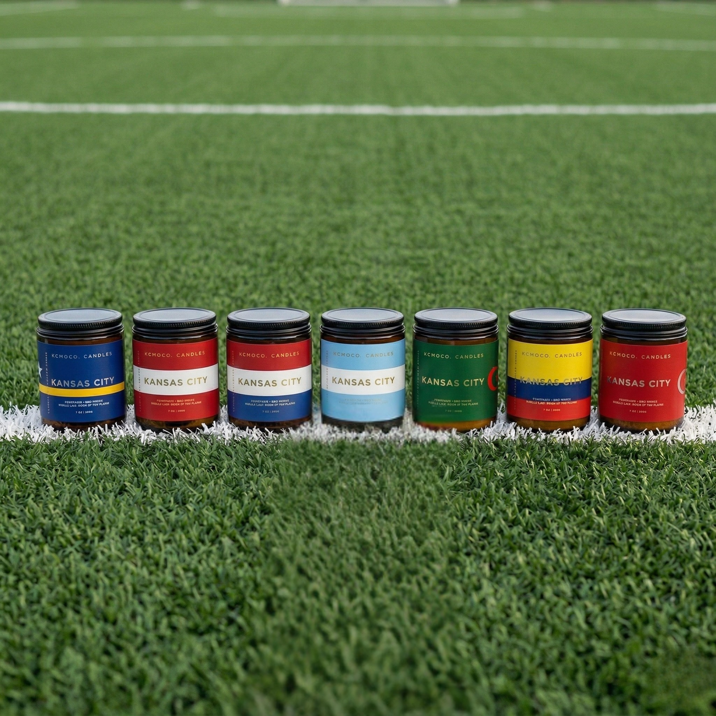 Row of Kansas City branded candles on a grassy field - world soccer event inspired jars with flag labels representing Algeria, Austria, Curacao, Netherlands, Argentina, Ecuador, and Tunisia