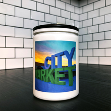 Load image into Gallery viewer, KCMOCO. City Market Candle in KC Collection Jar: White glass jar with photo label with photo of Kansas City&#39;s &quot;City Market&quot; sign, with black bamboo lid, on kitchen cabinet.
