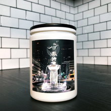 Load image into Gallery viewer, KCMOCO. Fountain City Candle in KC Collection Jar: White glass jar with photo label depicting David Woods Kemper Memorial Fountain aka Muse of the Missouri by Wheeler Williams, with black bamboo lid, on kitchen cabinet.
