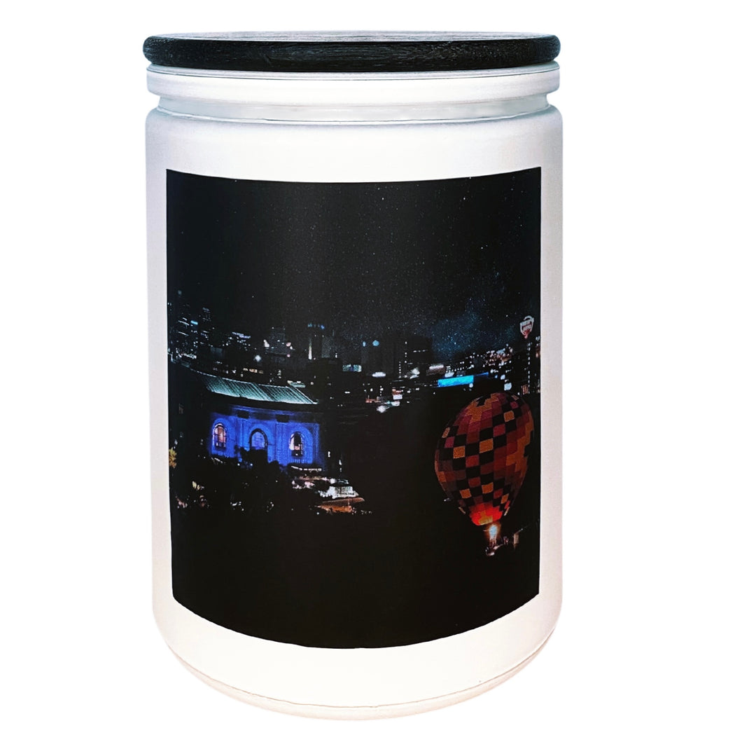 White candle jar with black lid and photo label depicting Kansas City Missouri Skyline at night with Union Station and a hot air balloon illuminated in the foreground
